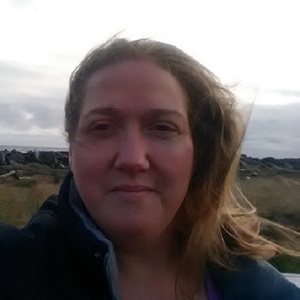 Karolyn H, book editor, in front of rock jetty near the ocean